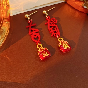 Detail shot of vintage red enamel lucky pouch earrings with gold tassels and calligraphy