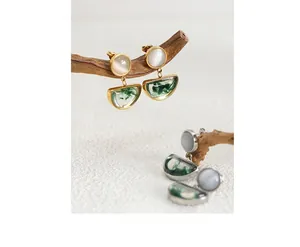 Detail of vintage gold and silver earrings with cat eye stones and green resin pendants