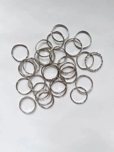 Flat lay of multiple minimalist silver geometric rings in various patterns on white background