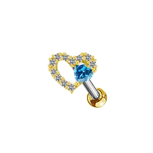 Macro detail of golden heart piercing stud with blue gemstone and white zirconia