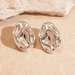 Macro shot of silver-colored irregular wavy earrings with a liquid metal texture