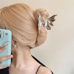 Close-up of a silver bat-shaped metal hair claw clip worn by a model for a stylish look