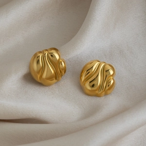 Détail de boucles d'oreilles rondes géométriques dorées 18K sur un tissu de soie crème