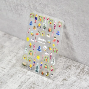 Macro detail of Christmas nail art stickers featuring Nutcracker and festive forest motifs