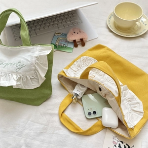 Flat lay detail showing ruffles and embroidery on green and yellow canvas lunch bags