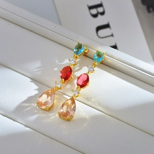Macro shot of luxury gold tiered earrings with sky blue, rose red and champagne gemstones