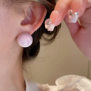 Macro detail of round pink and white marble texture stud earring worn on model ear