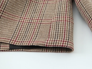 Macro shot of houndstooth plaid fabric texture in brown and beige with thick woven wool detail