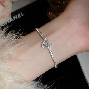 Detailed close-up of a delicate gold heart pendant bracelet worn on a woman's wrist