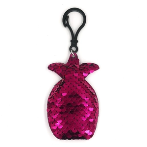 Close-up of a pink pineapple-shaped keychain with reflective sequins and a black hook