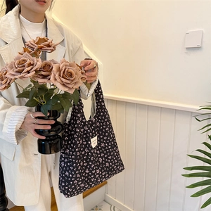 Detail of black floral canvas tote bag with pink flower pattern and woven square label