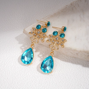 Detail of vintage gold earrings with blue water drop gems and zircon flower inlay