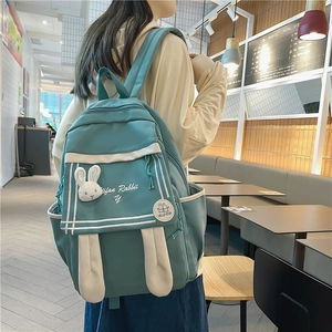Cute mint green nylon backpack with rabbit ears and plush toy charm in cafe setting