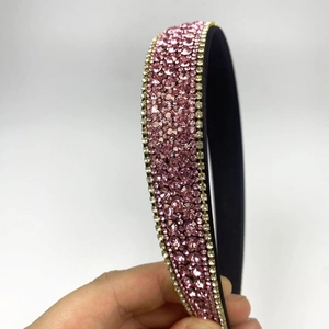 Macro shot of pink rhinestones and gold edge detail on a luxury headband accessory