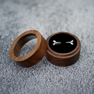 Detailed view of silver leaf earrings inside a round dark wooden jewelry gift box