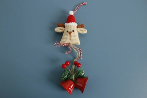 Macro detail of handmade crochet reindeer with red hat, golden bell and pine needle decor