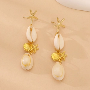 Detalle de pendientes colgantes de estrellas de mar doradas y conchas blancas de cauri