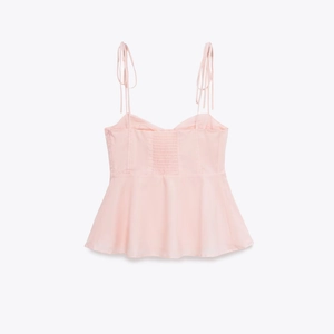 Dettaglio del canotta rosa chiaro con spalline regolabili e texture arricciata elastica