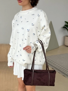 Floral knit sweater styled with a white pleated skirt and brown suede handbag