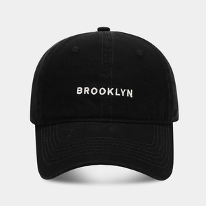 Close-up of white Brooklyn embroidery on a premium black cotton canvas baseball cap