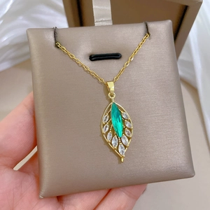 Detail of gold leaf necklace with green gemstone and pave crystals in a jewelry box