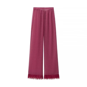 Détail du pantalon large fuchsia avec tissu métallisé scintillant et bordure en plumes