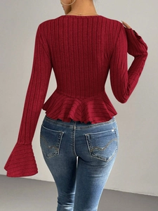 Detail of burgundy ribbed long-sleeved top featuring a peplum hem and flare sleeves