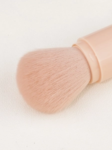 Macro shot of fluffy pink synthetic bristles and sleek handle of a 4-in-1 makeup brush