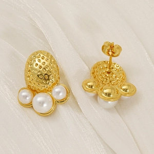 Macro view of gold octopus texture stud earrings with three white pearls detail