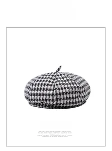 Detailed close-up of a classic black and white houndstooth beret in warm woolen fabric