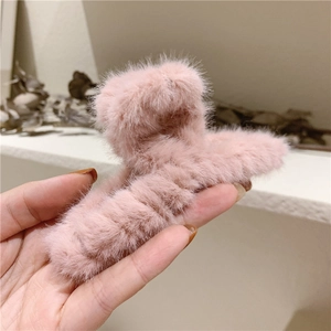 Gros plan d'une pince à cheveux en peluche rose douce en fausse fourrure pour l'hiver