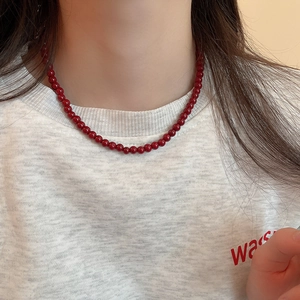Detail of minimalist vibrant red beaded necklace worn with a casual white t-shirt