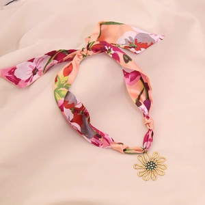 Macro view of the pink floral silk scarf necklace with golden hollow flower pendant