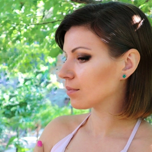 Gros plan d'élégantes boucles d'oreilles rondes vert émeraude portées par un mannequin