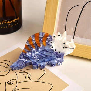 Detail of blue triceratops hair claw clip with marble texture and orange stripes