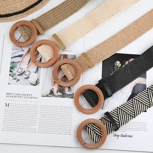 Detail view of woven straw belts with round buckles in various natural summer colors