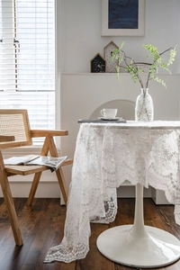 Detailed close-up of white lace tablecloth with floral embroidery and scalloped edges
