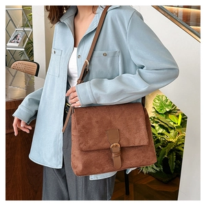 Close-up of vintage brown matte suede crossbody bag with bronze buckle and strap