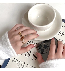 Close-up of golden chain and interlaced rings with white inlay on woman's hand