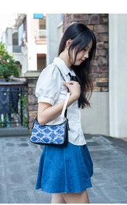 Close-up of blue geometric denim shoulder bag with black leather trim and gold hardware