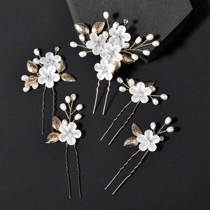Detail van 5-delige bruidshaarspelden set met gouden bladeren en witte matte bloemen