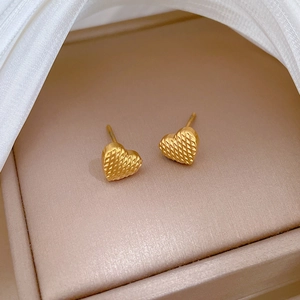 Minimalist gold titanium steel heart stud earrings with checkered texture on satin fabric