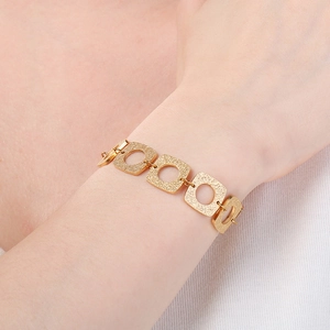 Détail du bracelet à maillons carrés évidés plaqué or 18K avec texture mate sur poignet