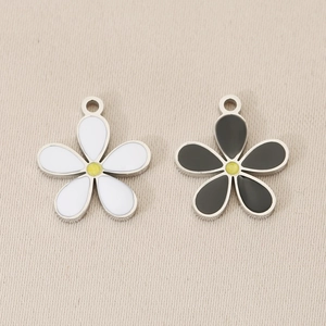 Detailed macro shot of 18K gold plated flower charms with white and black enamel petals