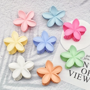 Set of 8 colorful matte frangipani flower hair claws in pastel tones on a soft fabric