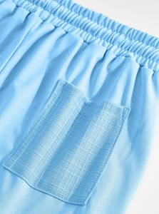 Detail of light blue casual shorts featuring elastic waistband and jacquard textured pocket