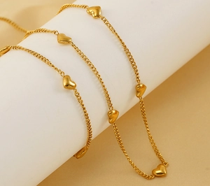 Primer plano del collar con colgantes de corazón dorado sobre soporte blanco