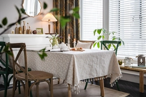 Detail of linen tablecloth with daisy floral print and elegant fringe tassels