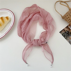 Pink gauze neck scarf with pearl charms and lace detail on a lifestyle flatlay background