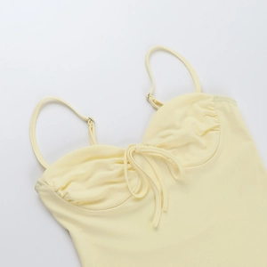 Dettaglio del costume da bagno giallo chiaro con spalline sottili e fiocco sul petto